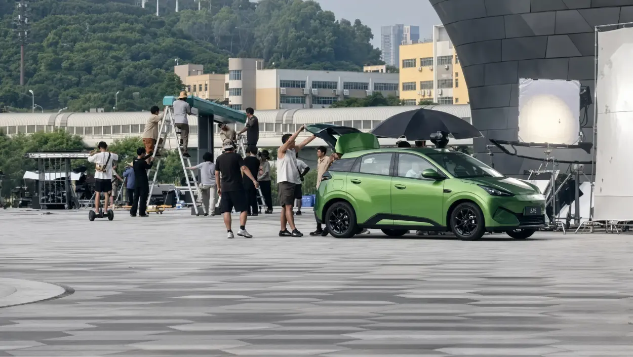 The second-generation BYD Seagull photographed uncovered on a plaza during a shoot, with a film crew and lighting rig